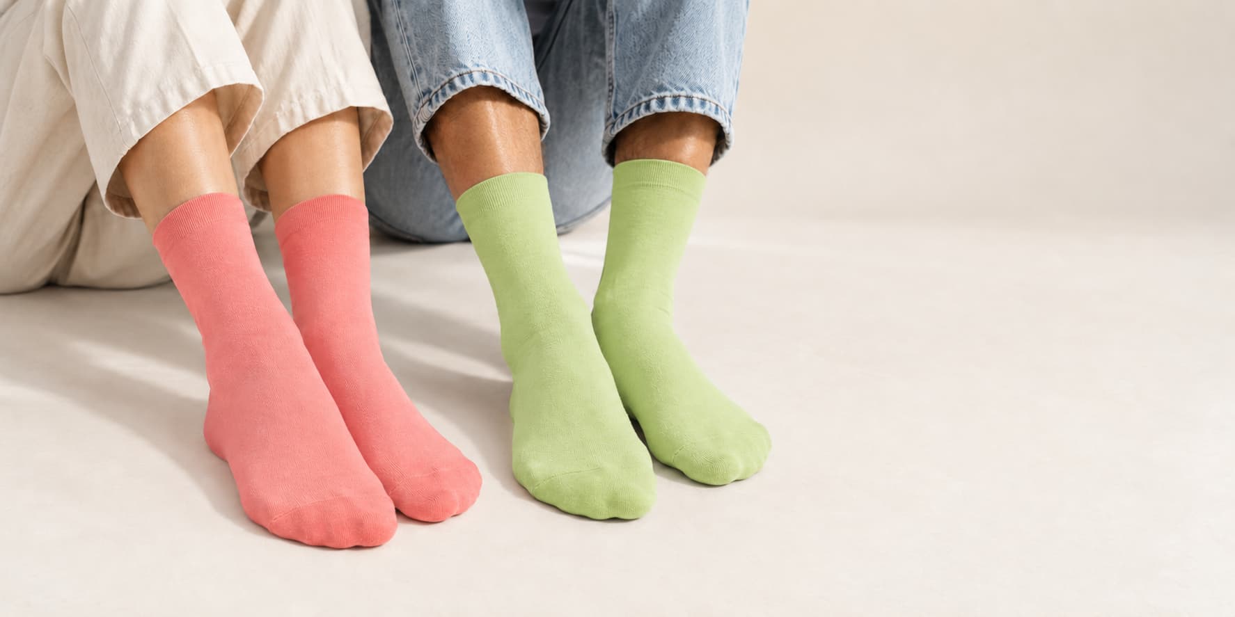 One men and women wearing pairs of coral pink and sage green ogranic cotton socks.